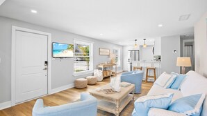 A spacious living room with a large TV, a wooden coffee table, and a sofa. - Book Magnolia Shores: Family-Friendly Getaway Near Beach with Pool and Mini Golf (Anna Maria)