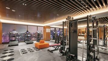 A gym with treadmills, weight machines, and orange seating.