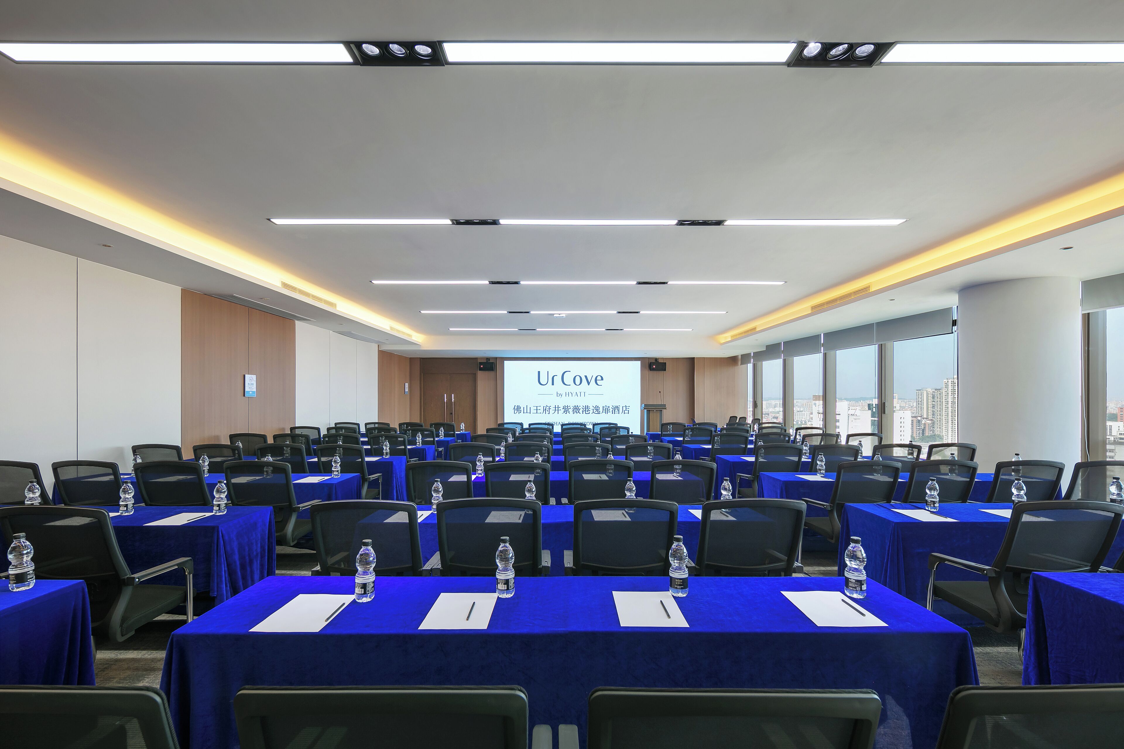 Un salón de conferencias con varias mesas, sillas y botellas de agua.