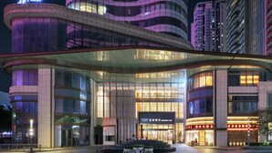 A modern hotel with a curved glass facade, large windows, and a prominent entrance. - UrCove by Hyatt Foshan Downtown (Foshan)