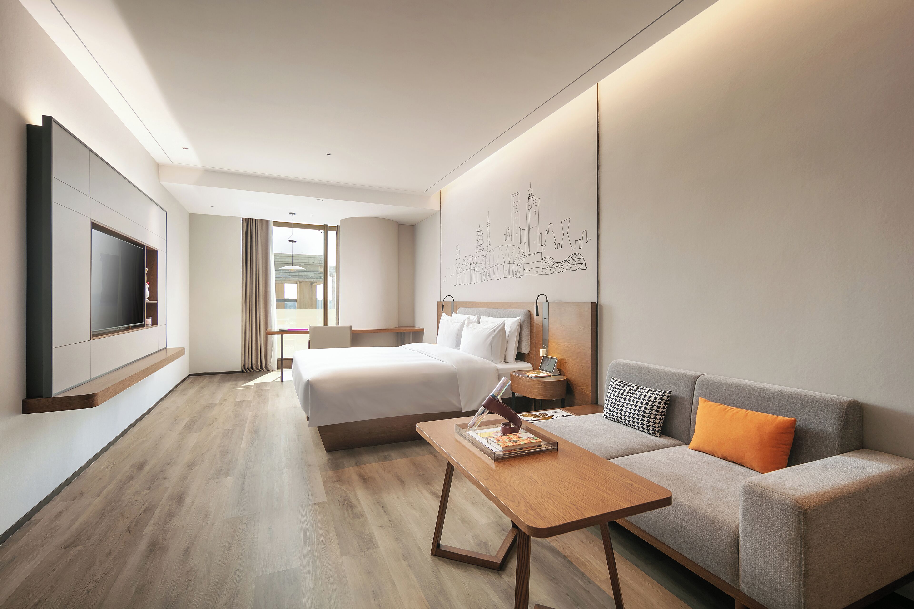 Une chambre d’hôtel comprenant un lit, un canapé, une télévision, un bureau et une œuvre d’art murale.