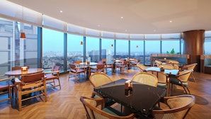 A modern restaurant with high ceilings, large windows, and a panoramic city view. - UrCove by Hyatt Foshan Downtown (Foshan)