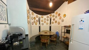 Une cuisine avec une table ronde, des chaises, un réfrigérateur et un mur décoré d’assiettes.