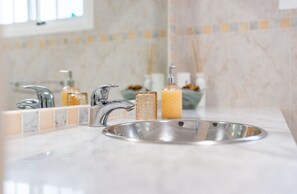Ein Badezimmer mit Marmorwaschbecken, zwei Wasserhähnen und einer Seifenspender.