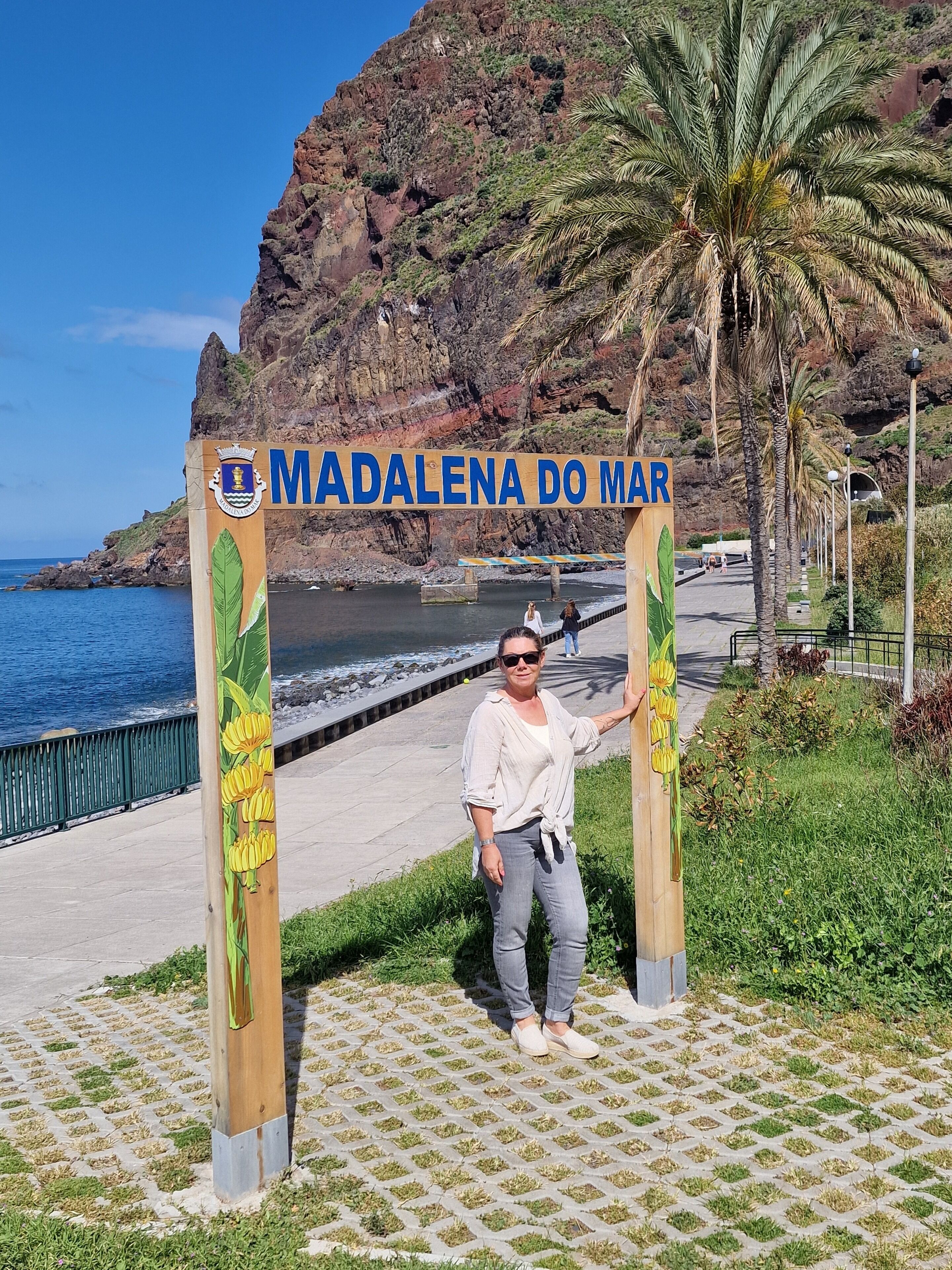A sign with 'MADALENA DO MAR' and a coastal view with palm trees and a rocky cliff.