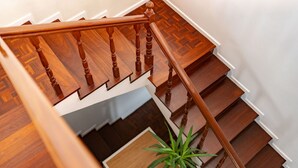 Un escalier en bois, doté d’une rampe et orné d’une plante en pot à sa base.