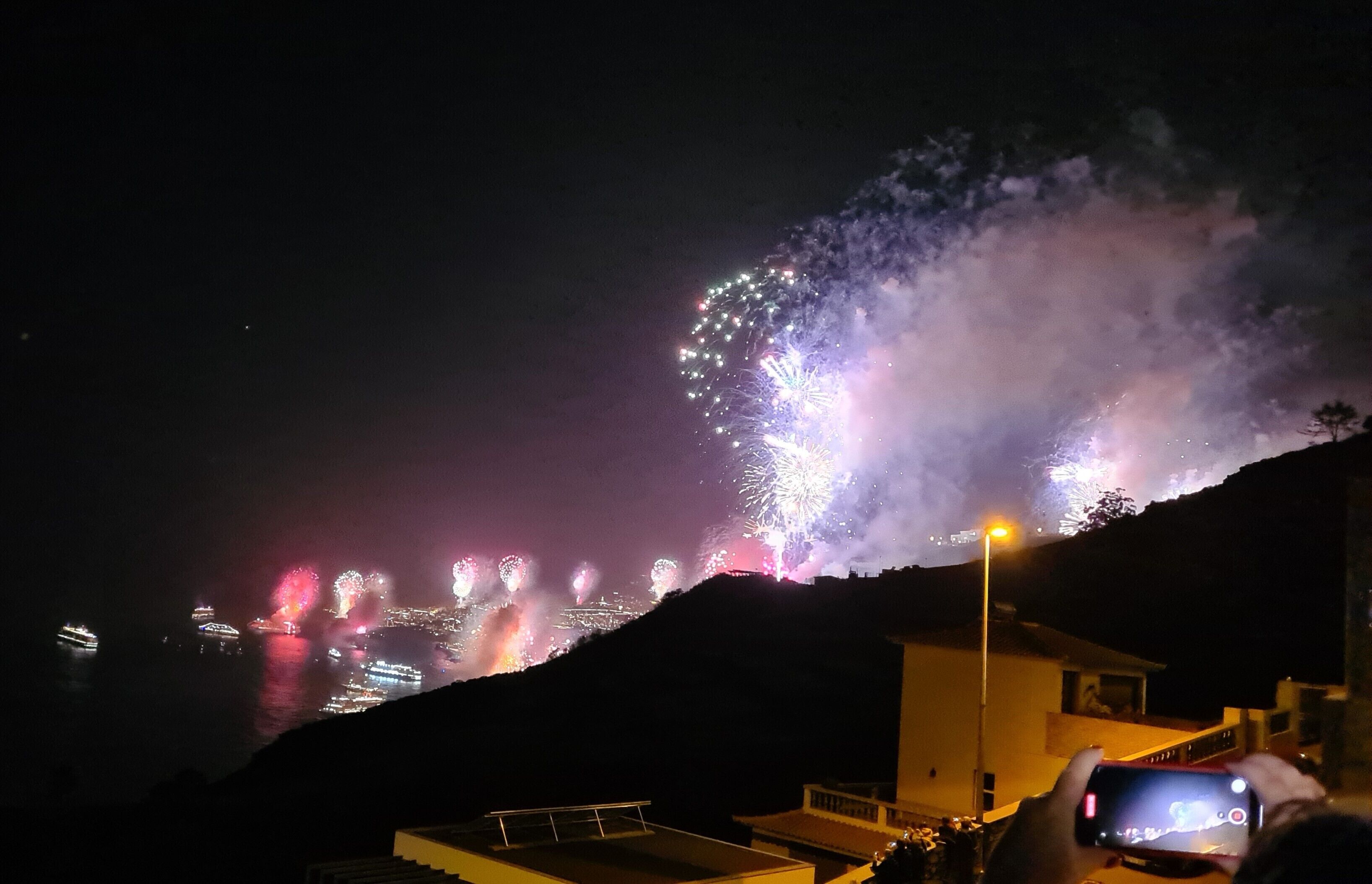 Une vue nocturne d’une zone côtière illuminée par un feu d’artifice.
