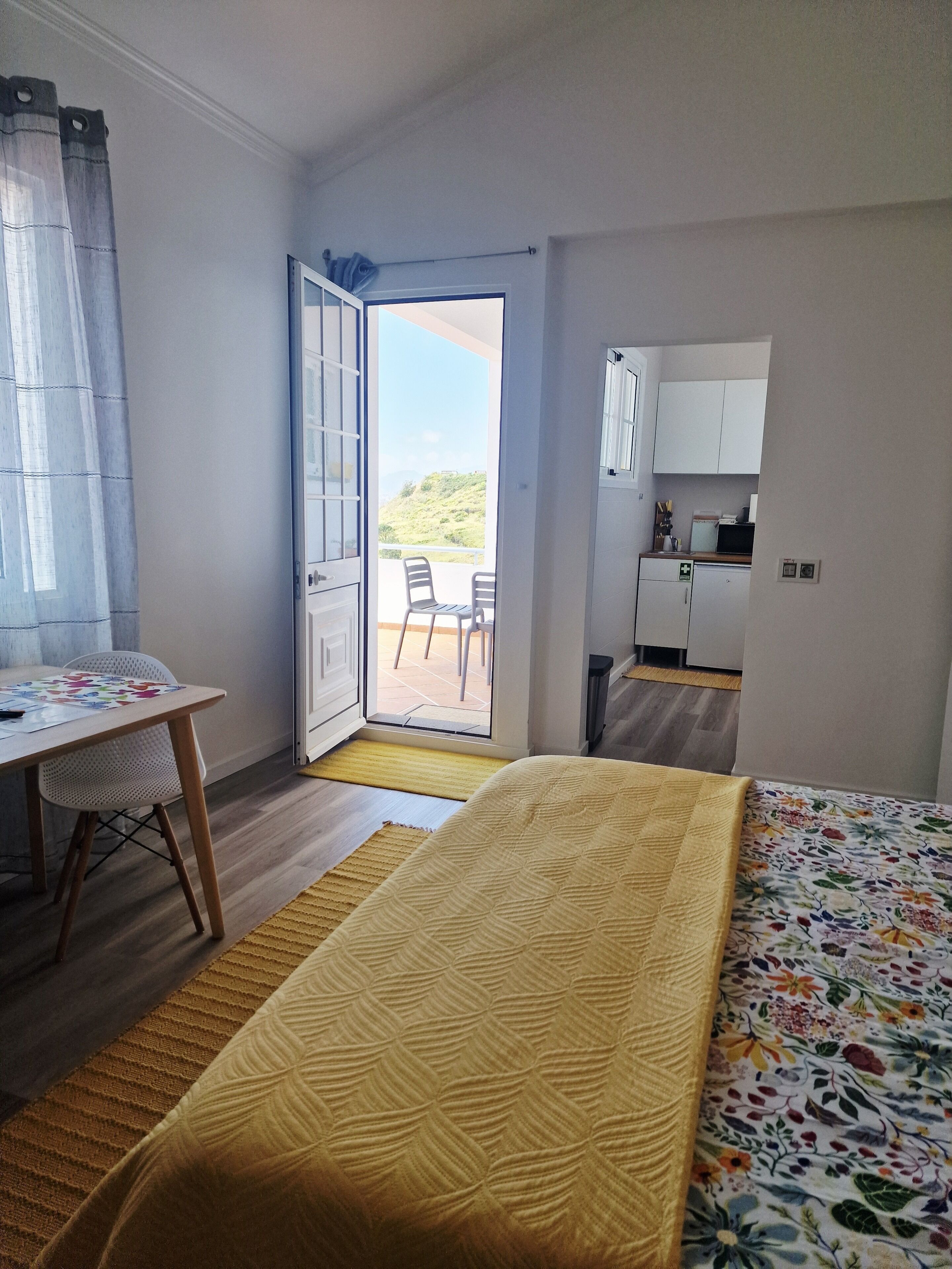 Une chambre d’hôtel comprenant un lit, un bureau, une chaise, une petite kitchenette et un balcon avec vue.