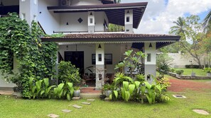 A two-story building with a covered porch, potted plants, and a well-maintained lawn.