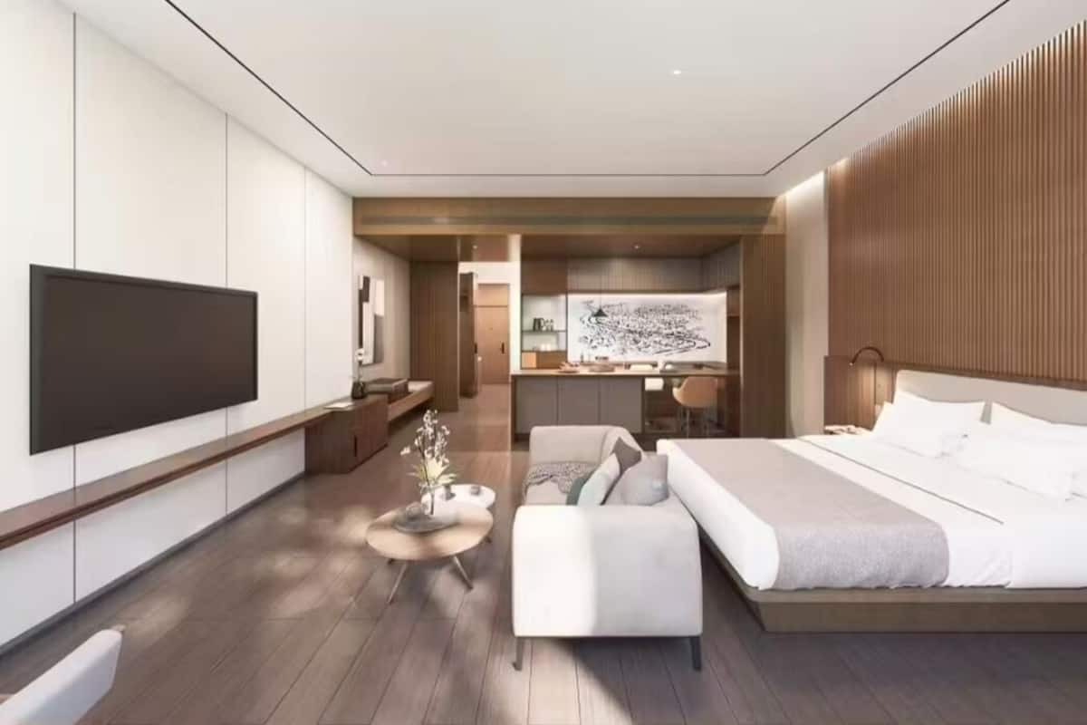 A modern hotel room with a large bed, a flat-screen TV, a desk, and a seating area.