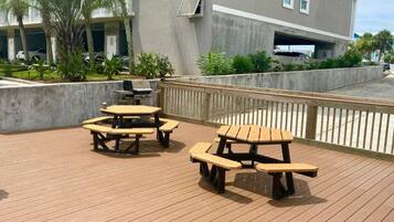 Eine Holzterrasse mit Picknicktischen und einer Betonmauer.