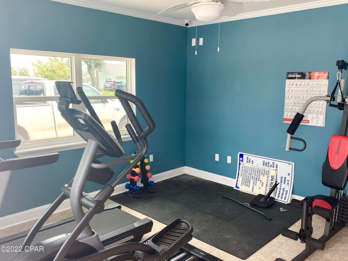 A gym with a treadmill, weight bench, and exercise balls.