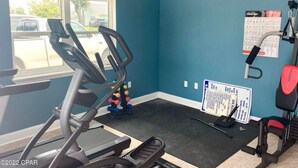 Un gimnasio con cinta de correr, banco de pesas y pelotas de ejercicio.