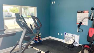 A gym with a treadmill, weight bench, and exercise balls.