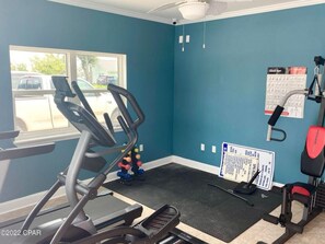 Un gimnasio con cinta de correr, banco de pesas y pelotas de ejercicio.