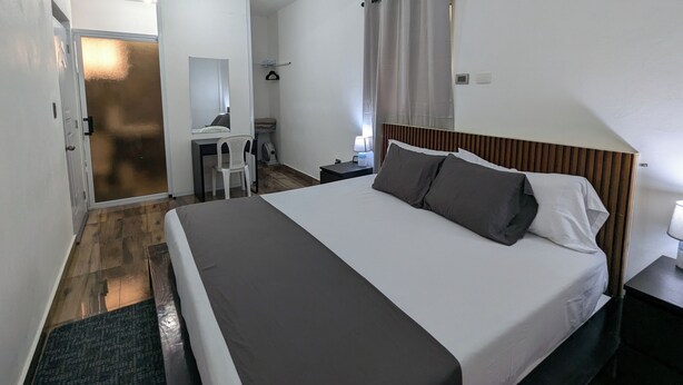 Una habitación de hotel moderna con una cama grande, un escritorio con una silla, un armario y un baño.