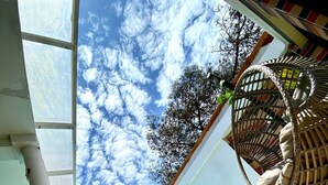 A pool area with a clear view of the sky, a hanging chair, and a tiled floor.