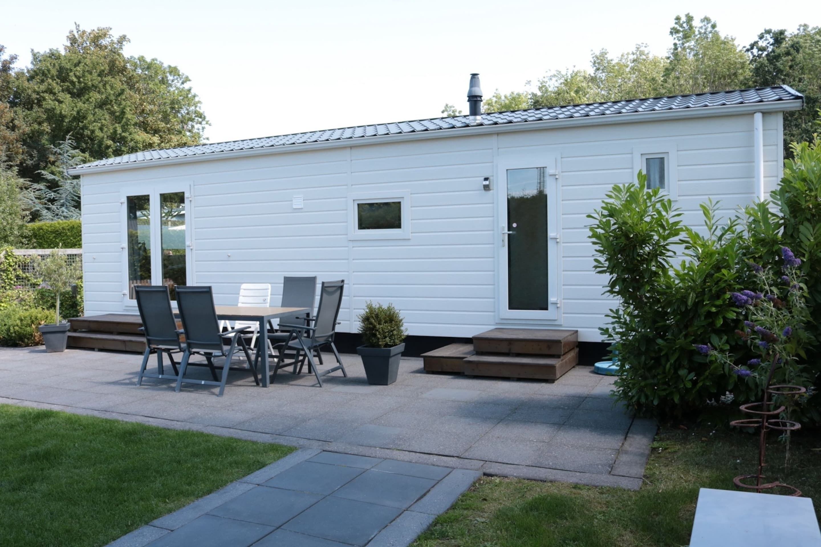 Une petite maison mobile d’un seul étage, dotée d’une terrasse avec une table et des chaises.