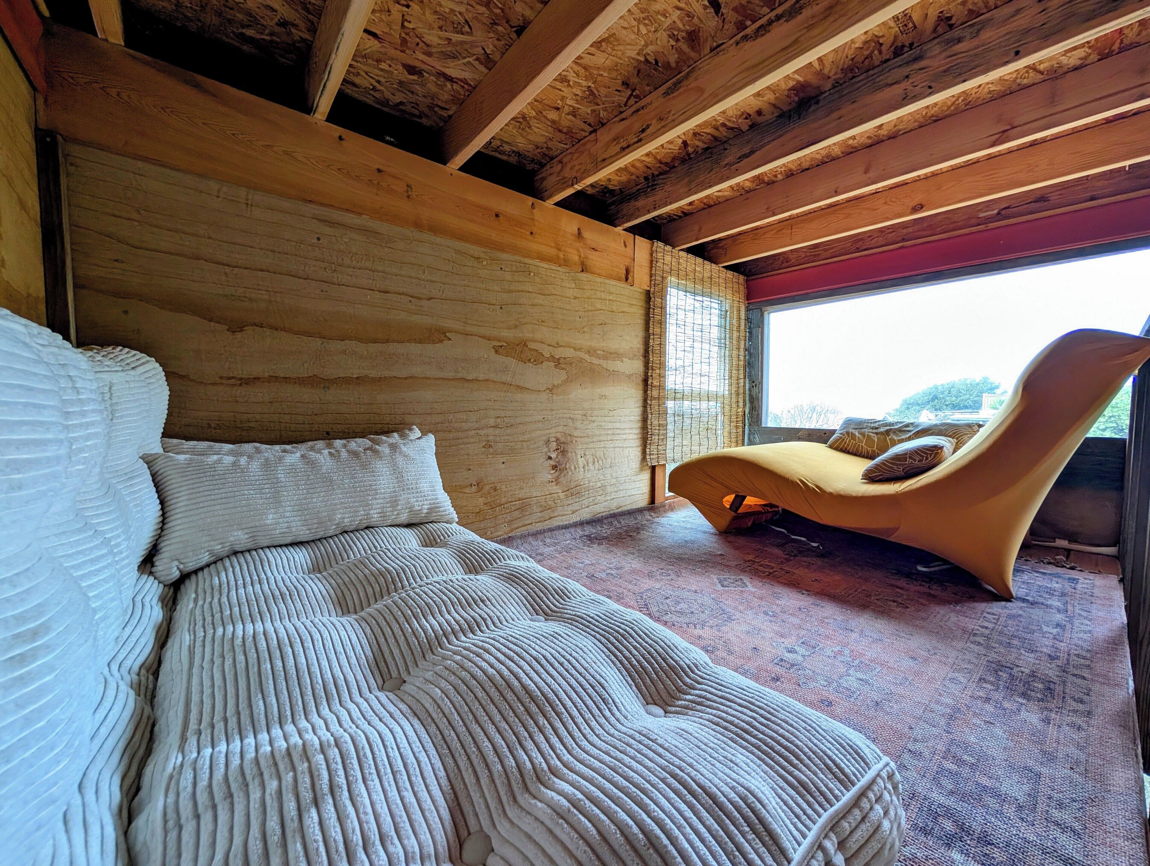 Un dormitorio con cama, una silla y una ventana.