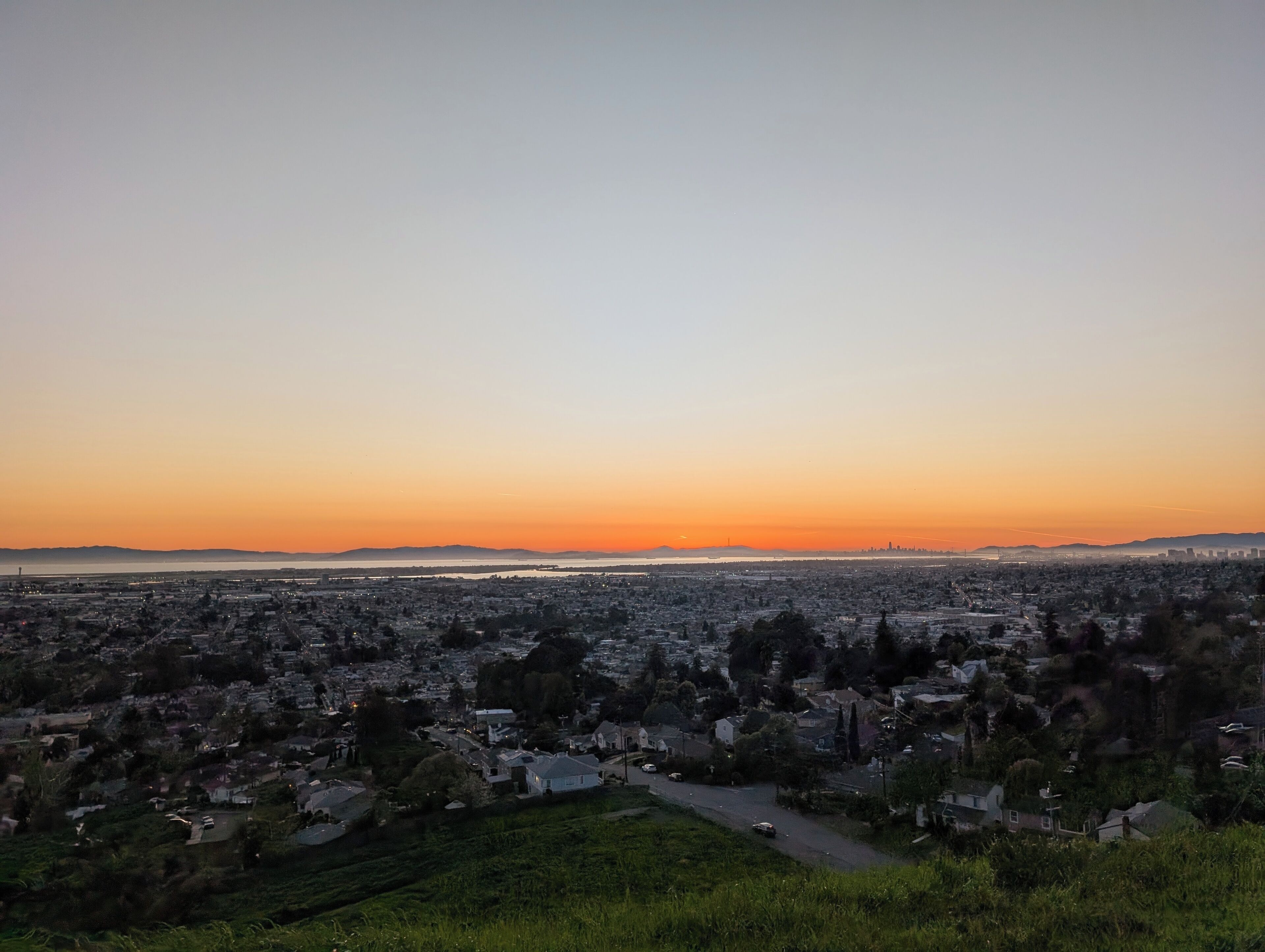 Un paisaje urbano al atardecer, con vistas al agua y montañas lejanas.