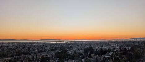 Un paisaje urbano al atardecer, con vistas al agua y montañas lejanas.