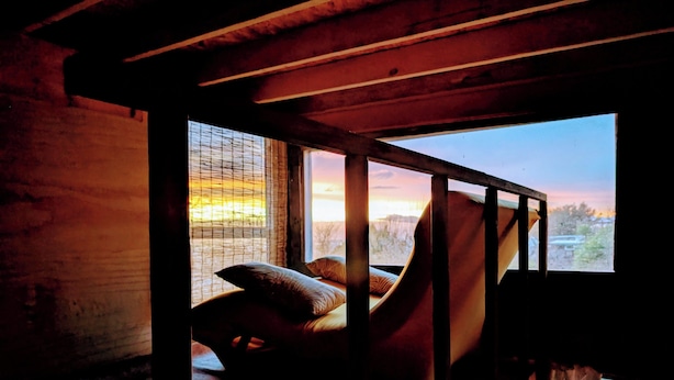 A rustic room with a wooden bed, a window with a view of the outdoors, and a wooden ceiling. - Hills Cottage with Panoramic Views & Hot Tub. Pet Friendly! (Oakland)