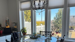 A dining area with a round glass table, black chairs, and a decorative chandelier. - Harbor Water View. Downtown. Beaches & waterfront playground +Cape Cod gateway! (Plymouth)