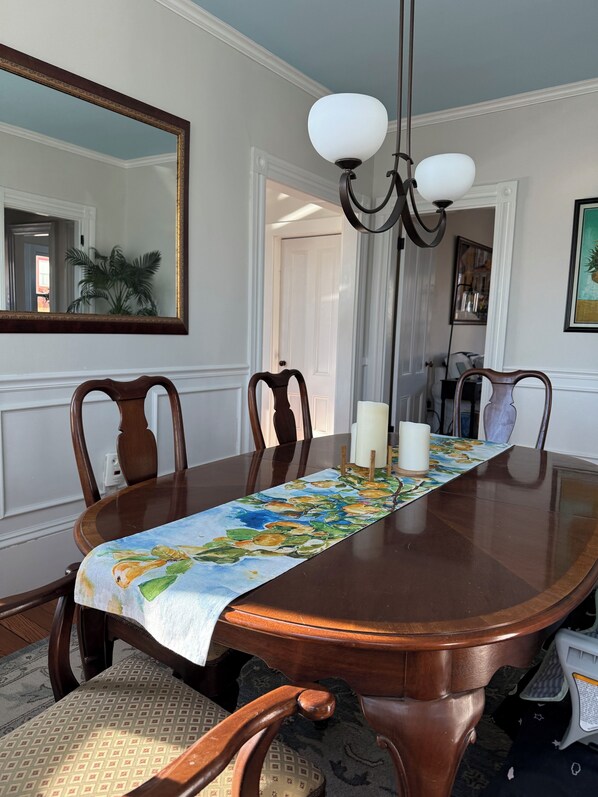 A dining room with a wooden table, chairs, a chandelier, and a mirror on the wall. - Harbor Water View. Downtown. Beaches & waterfront playground +Cape Cod gateway! (Plymouth)