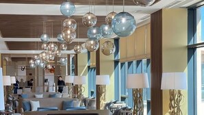 Un moderno vestíbulo de hotel con techo de madera, varias zonas de estar y grandes ventanales.