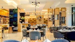 Un comedor moderno con mesas redondas, sillas tapizadas en azul y un columnario central de madera.