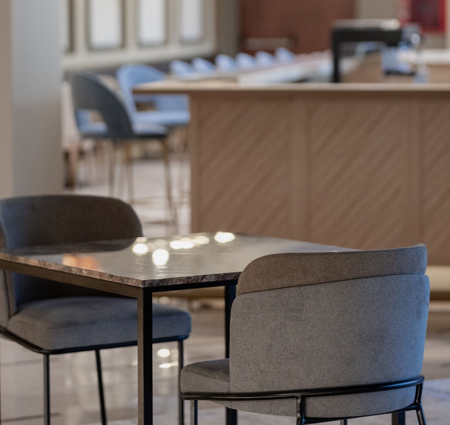 Zona de bar moderna con barra, dos taburetes y una mesa con sillas.