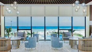 Amplia habitación con grandes ventanales con vistas a la playa, con muebles modernos y techo de madera.