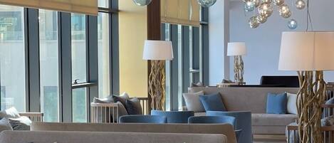 A modern hotel lobby with seating areas, large windows, and decorative spherical light fixtures.