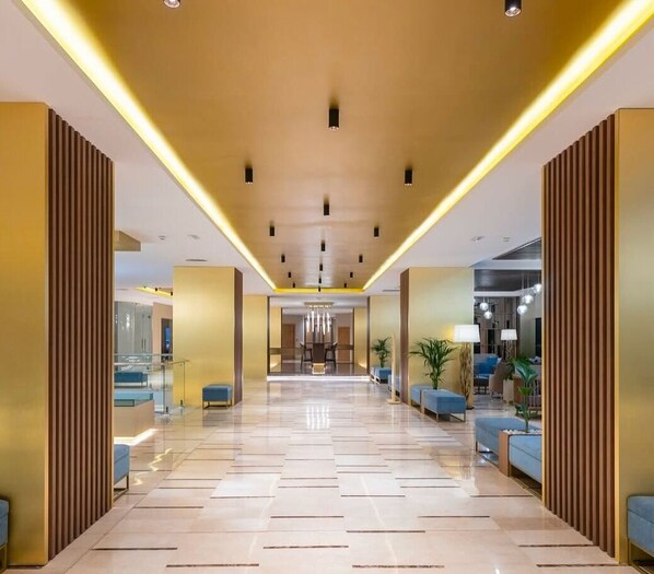 A modern hotel lobby with a central reception area, seating arrangements, and a clear pathway leading to the entrance. - Azur Rotana Thalasso & Resort (Mers El Hadjadj)