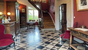 Une vaste pièce dotée d’un sol à carreaux, d’un escalier et d’un lustre.
