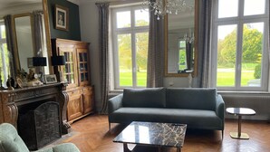Un salon spacieux avec un canapé vert, une table basse en marbre et une cheminée.