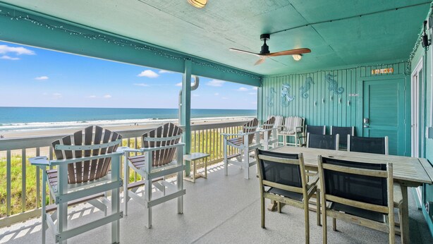 Un espace extérieur abrité, avec des chaises et une table, offrant une vue sur la plage.
