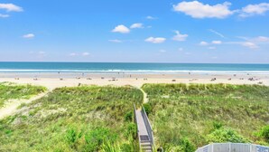 Une plage avec une promenade en bois qui mène à l’eau, entourée de dunes.