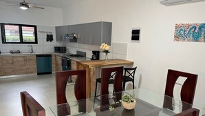 Una cocina moderna con armarios grises, una mesa de comedor de madera y una mesa con cubierta de vidrio.