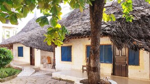 Un bâtiment traditionnel à toit de chaume, doté d’une cour dallée et d’un jardon.