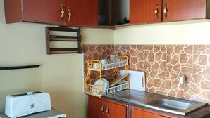 Une cuisine compacte avec des meubles en bois, un four encastré, un grille-pain et un pare-feu en pierre.