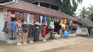 Une petite boutique dont le toit est fait de tôle ondulée, où sont exposés divers tissus et accessoires aux couleurs vives.