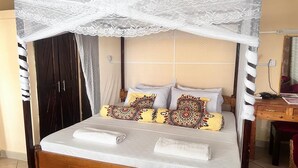 Un lit à baldaquin, avec une tête de lit en bois et des coussins à motifs.