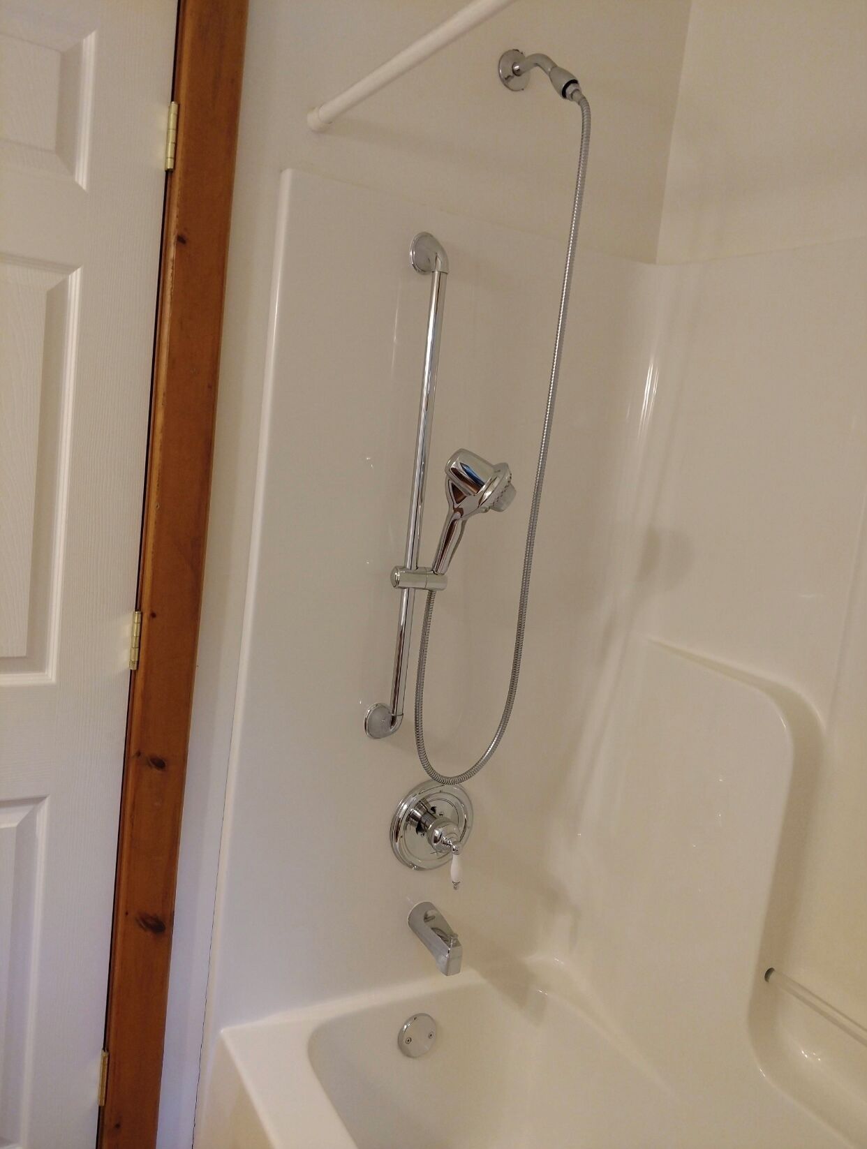 A bathroom with a bathtub, a shower with a handheld showerhead, and a handheld shower attachment.