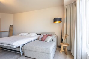 Une chambre à coucher moderne avec un lit, une table de chevet, une lampe et des rideaux.