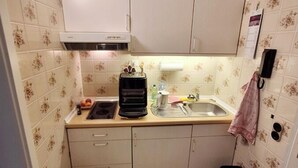 A compact kitchen with a sink, stove, and cabinets. - Vacation apartment Storm am Holm (Schönberg)