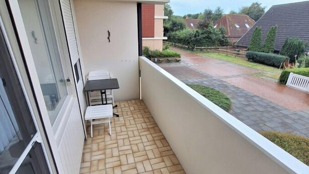 A small balcony with a tiled floor, a table, and a chair. - Vacation apartment Storm am Holm (Schönberg)