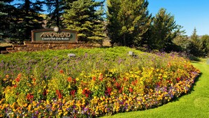 Een bord van Arrowhead Country Club of the Rockies, omringd door een kleurrijke bloementuin.