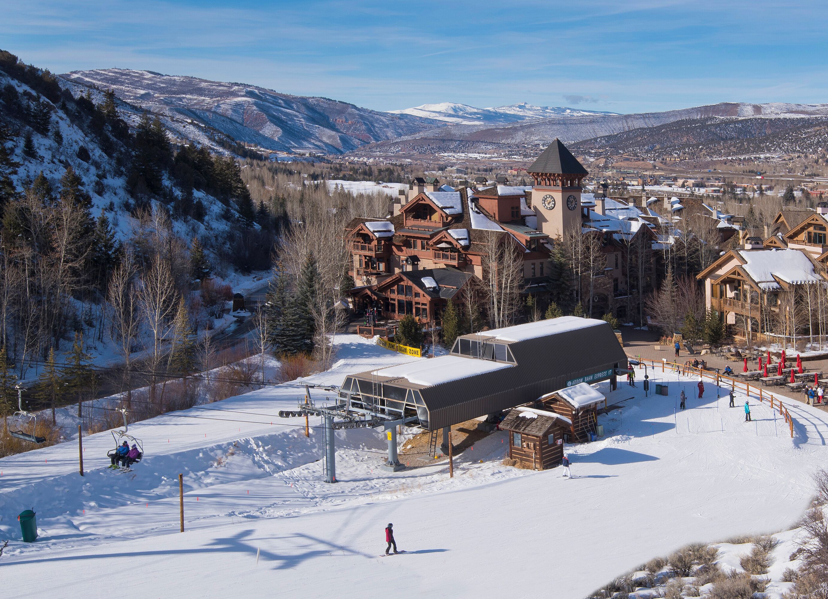 A ski resort with wooden lodges, a ski lift, and a snow-covered mountain backdrop.