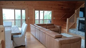 A cozy cabin interior with a wooden interior, a sofa, a dining table, and a fireplace. - THE LAZY BEAR, A luxury log cabin nestled in the heart of Maggie Valley. (Maggie Valley)
